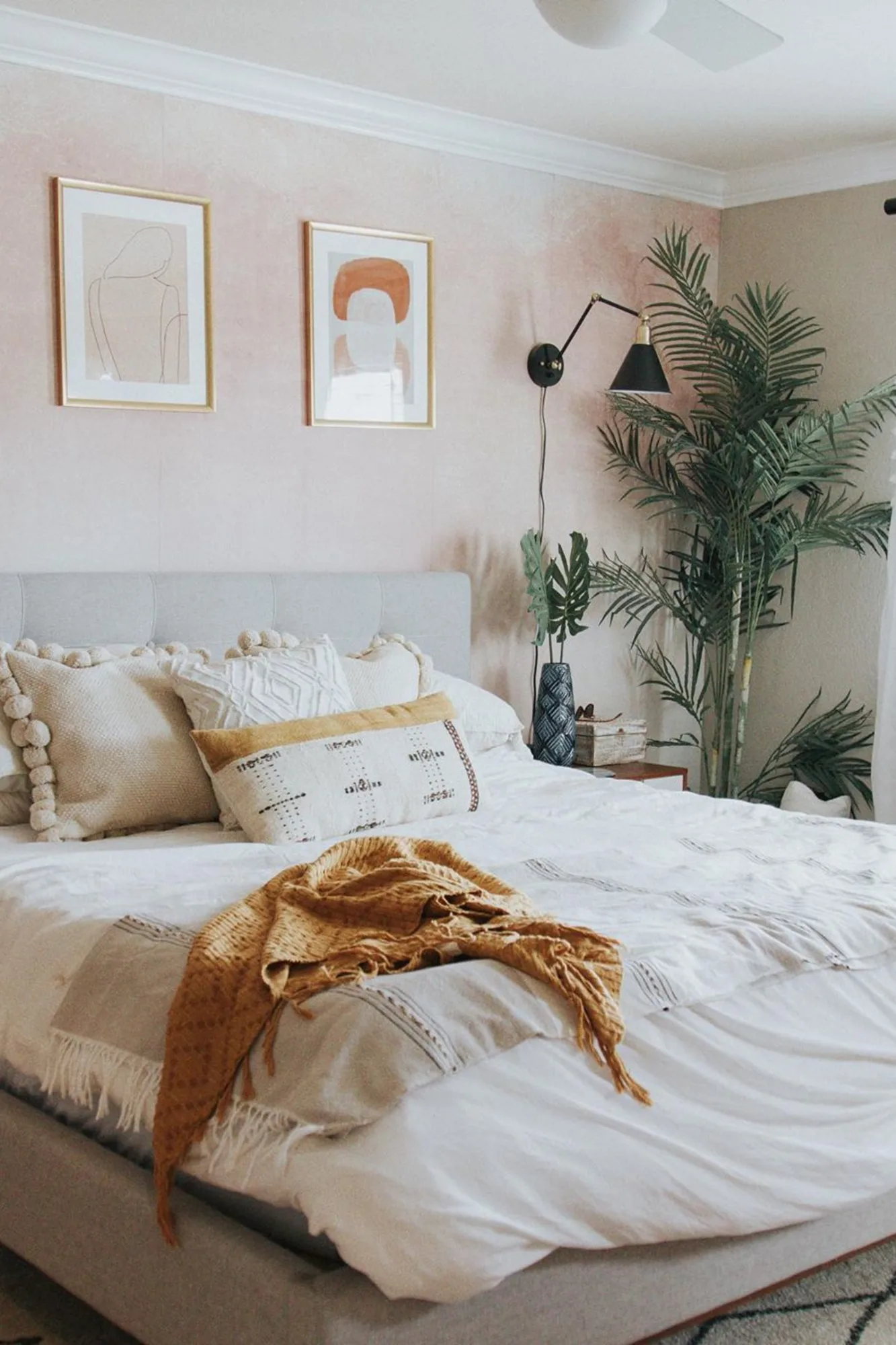 A soft pink ombre mural in a relaxed bedroom styled with boho decor and greenery.