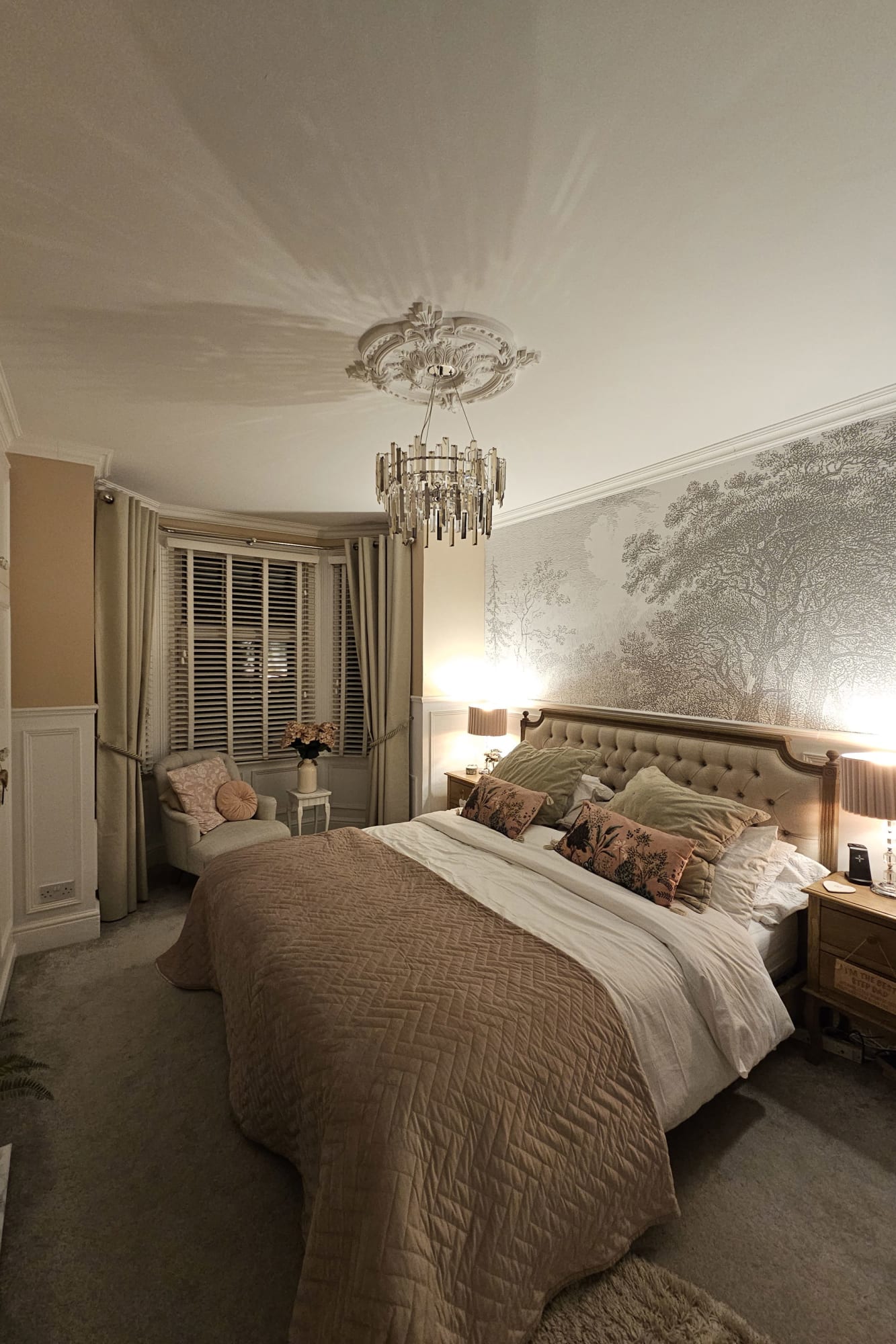 A traditional bedroom with a soft gray woodland mural and a tufted headboard.
