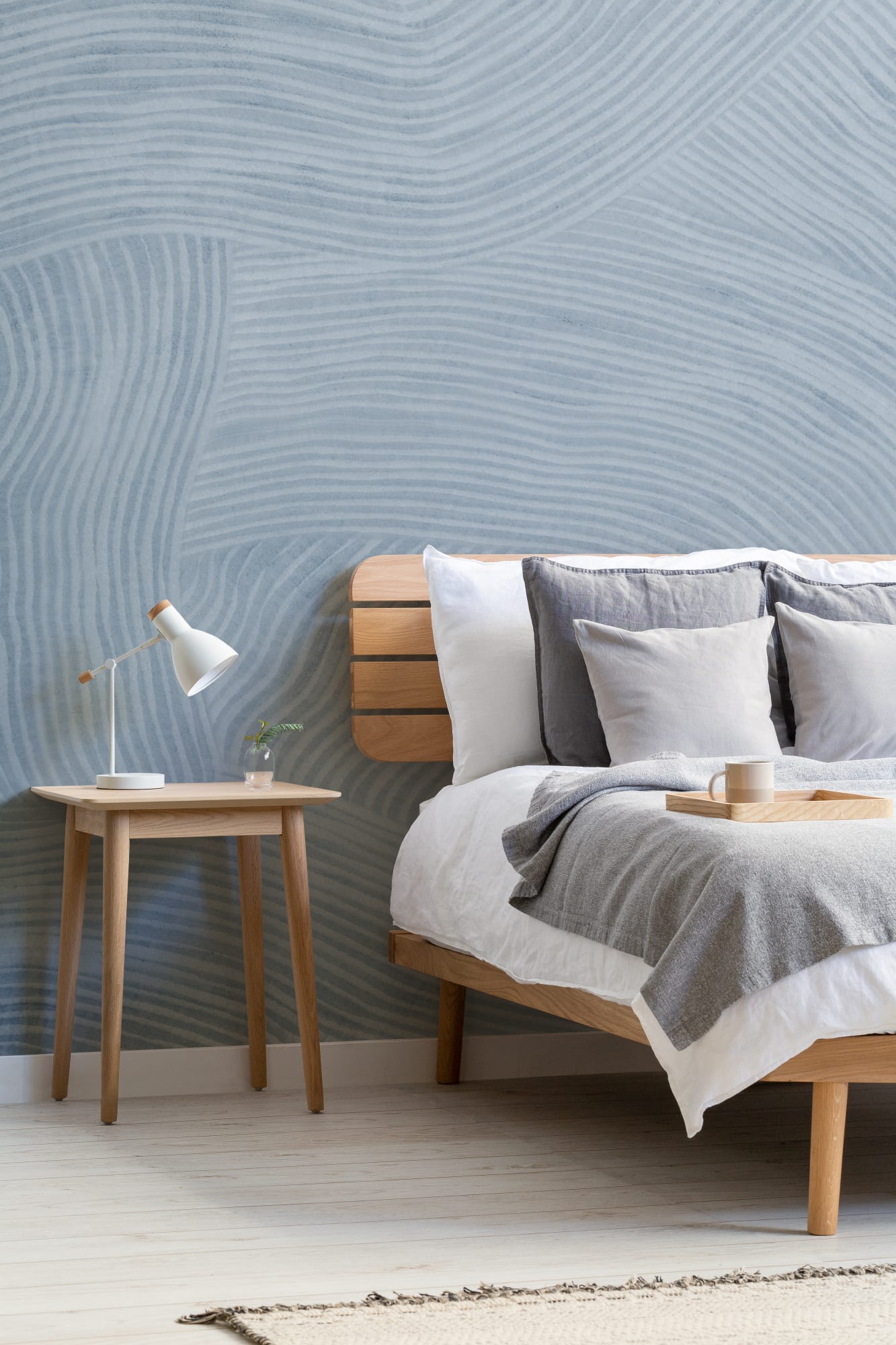 A Scandinavian-style bedroom with pale blue striped wallpaper and natural wood furniture.